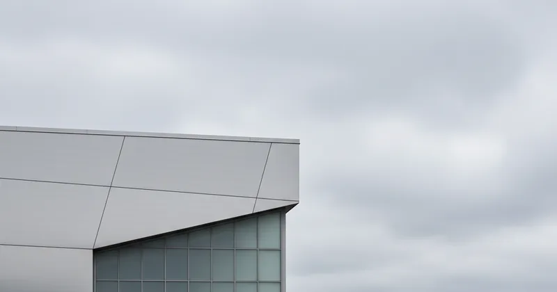 neutral architectural abstract of a modern building corner against a grey sky