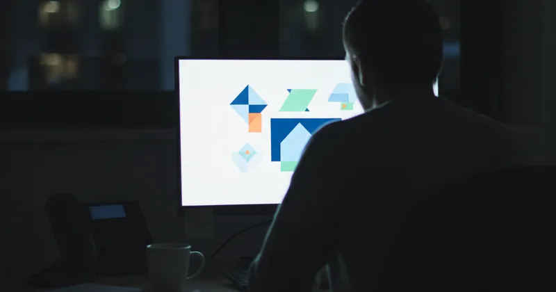 dim office at night with a glowing screen showing abstract dashboard shapes, no readable text